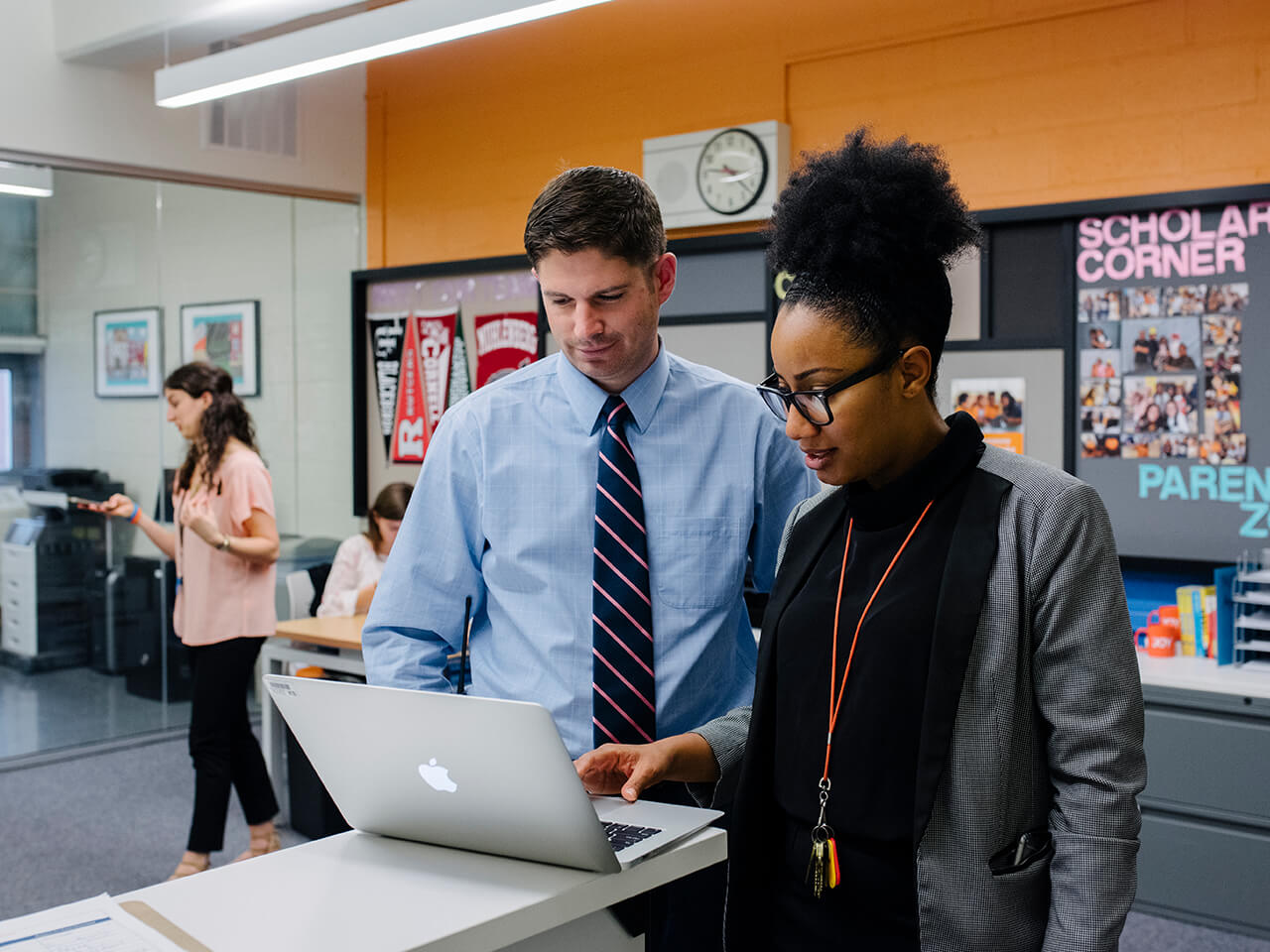 Two people collaborate on a laptop in an office.