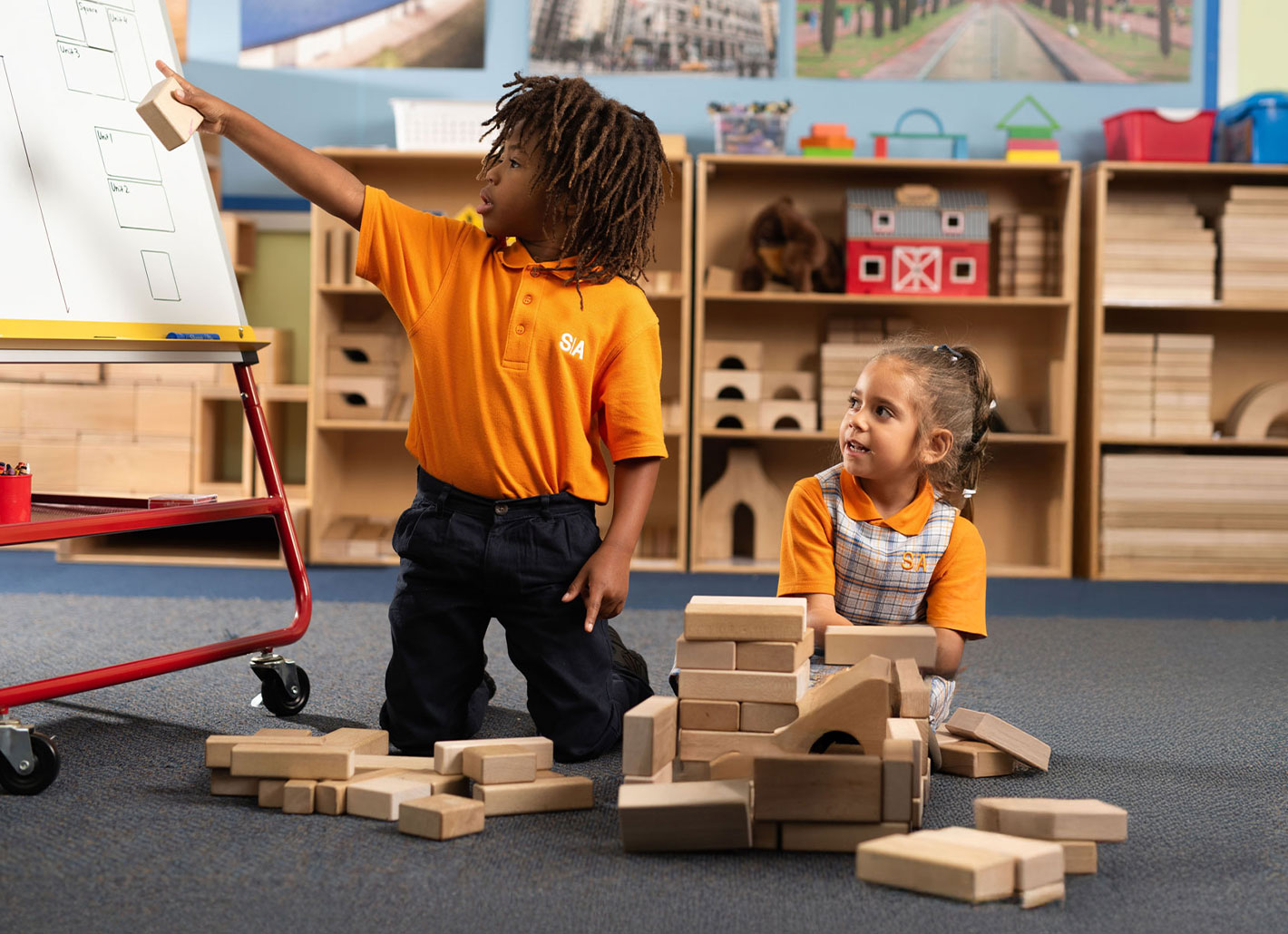 Elementary school student reaching for a book on a wooden library shelf in a brightly lit Success Academy classroom.